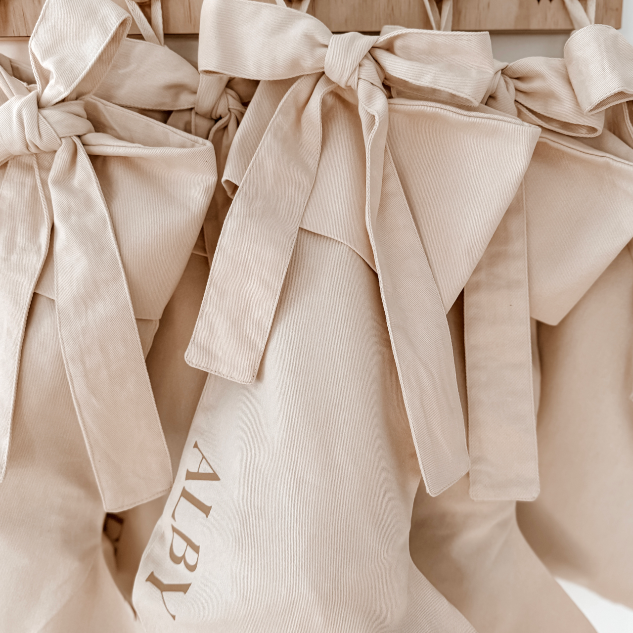 Personalised Christmas canvas bow stocking. Custom Christmas neutral stocking with bow. Minimalist bow Christmas stocking. Bow Name Christmas stocking. Personalised beige stocking with bow. Personalised cotton neutral bow stocking.