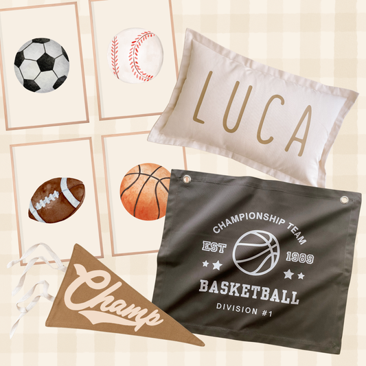 A coordinated sports-themed home decor set on a beige plaid background, including a white personalized pillow with the name LUCA, a dark gray basketball banner reading Championship Team Basketball, a brown pennant with Champ script, and small framed sports ball illustrations.